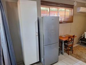 einen Kühlschrank aus Edelstahl in einer Küche mit einem Tisch in der Unterkunft 1@Kruger in Mokopane