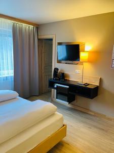 a hotel room with a bed and a desk with a television at L-DOM in Metzingen