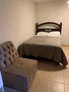 a bedroom with a bed and a ottoman next to a couch at Céntrico y acogedor apartamento in Cajamarca