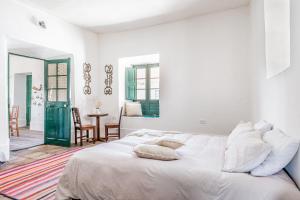 a white bedroom with a large bed and a table at Fundo Chincheros Lodge in Juliaca