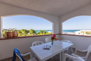 a white table and chairs in a room with two windows at Village La Canzone del Mare in Vieste
