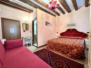 - une chambre avec un lit rouge et un canapé dans l'établissement Alloggi Serena, à Venise