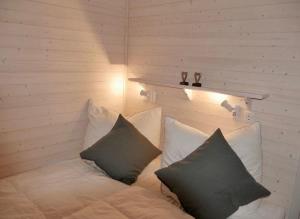 a bed with three pillows on it in a room at Hausboot ELLA- Huus & Meer in Burgstaaken