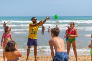 a group of people playing with a frisbee on the beach at Village La Canzone del Mare in Vieste