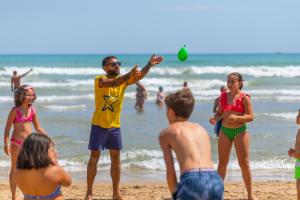 ヴィエステにあるVillage La Canzone del Mareの海辺でフリスビーと遊ぶ集団