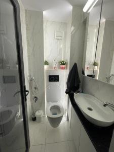 a white bathroom with a toilet and a sink at Apartament Central Tulcea in Tulcea