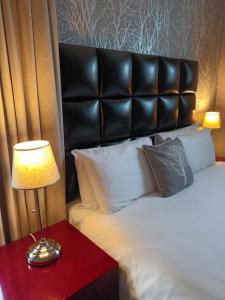 a bed with a black headboard and a lamp on a table at The Royal Hotel Cardiff in Cardiff