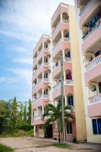 a pink building with a palm tree in front of it at Clarine Cozy Holiday Home in Mtwapa