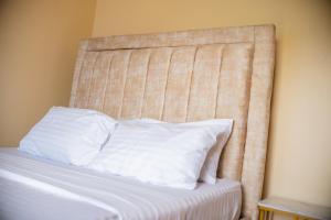 a bed with a head board with white pillows at Clarine Cozy Holiday Home in Mtwapa