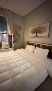 a large white bed in a bedroom with a window at كوخ الشاطئ جمال الحاضر والطبيعة in Jazan