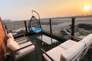 a porch with chairs and a swing on a balcony at كوخ الشاطئ جمال الحاضر والطبيعة in Jazan