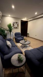 a living room with blue couches and a table at كوخ الشاطئ جمال الحاضر والطبيعة in Jazan