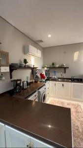 a kitchen with white cabinets and a black counter top at كوخ الشاطئ جمال الحاضر والطبيعة in Jazan