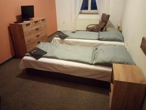 Duas camas num quarto com uma cadeira e uma cómoda em Penzion Prajzko, Hronov em Hronov