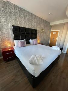 a bedroom with a large bed with a black headboard at The Royal Hotel Cardiff in Cardiff