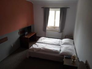 een kleine slaapkamer met een bed en een raam bij Penzion Prajzko, Hronov in Hronov
