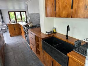 a kitchen with a large sink and wooden cabinets at Clarens Tranquil Mountain Villa in Clarens