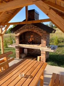a brick fireplace with a wooden table and a bench at Vikendica Ivana in Livno