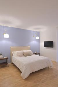 Un dormitorio blanco con una cama y un televisor de pantalla plana. en Mediterranea Home Napoli, en Nápoles
