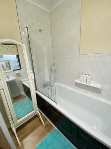 y baño con ducha y bañera con espejo. en Barking London House sleeps 11 - parking - train tube - airport, en Londres