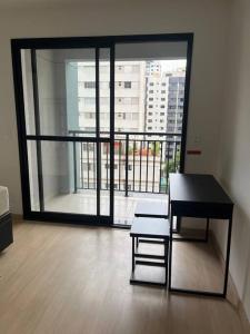 einen Tisch und einen Stuhl in einem Zimmer mit einem großen Fenster in der Unterkunft Studio ao lado Allianz parque in São Paulo