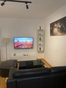 uma sala de estar com um sofá e uma televisão de ecrã plano em Cozy Apartment em Tirana