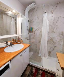 uma casa de banho branca com um chuveiro e um lavatório. em Riverside Retreat with balcony & parking em Courbevoie