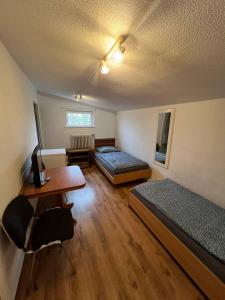 a room with two beds and a desk and a table at Messe und Monteurzimmer Sehnde in Sehnde