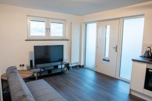 a living room with a couch and a flat screen tv at The Porty Beach House in Edinburgh