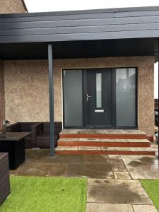 a house with a black door and some grass at The Beach House in Edinburgh