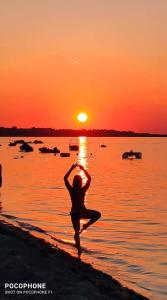 kobieta uprawiająca jogę na plaży o zachodzie słońca w obiekcie Apartment Selman w Nin