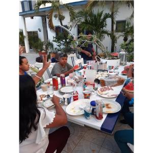 a group of people sitting around a table eating food at Palmita Hotel Hostel in Oranjestad