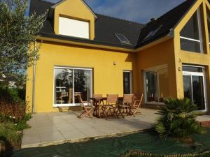 een geel huis met een patio met een tafel en stoelen bij Charmante maison moderne entre terre et mer in Coray