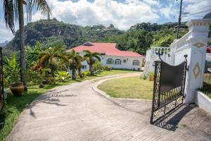 um portão para uma casa com uma montanha ao fundo em Beau Soleil Stunning Sea View One Bedroom Apartment em Mahé