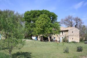 uma velha casa de pedra num campo com uma árvore em La Crozette - Mas Provençal em Saint-Restitut