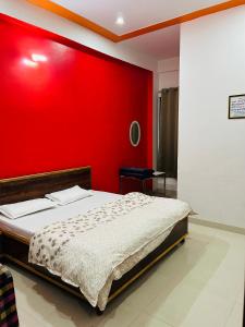 Un dormitorio con una pared roja y una cama en Prem Bhawan Guest House en Khātu