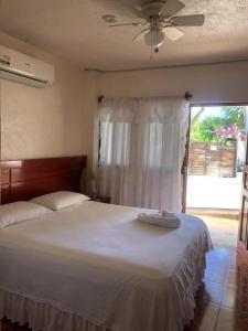 1 dormitorio con 1 cama blanca grande y ventilador de techo en Casa de Huespedes Milena, en Puerto Baquerizo Moreno