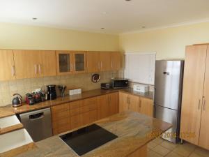 a kitchen with wooden cabinets and a stainless steel refrigerator at 25 Sunset View in Langstrand +16 photos
