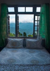uma cama num quarto com uma grande janela em Happy feet homestay em Kalimpong
