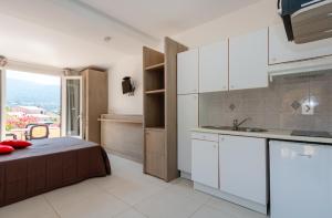 um quarto com uma cama e uma cozinha com uma janela em Hôtel et Résidence Ta Kladia - Omigna em Cargèse