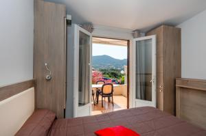 - une chambre avec un lit et un balcon avec une table dans l'établissement Hôtel et Résidence Ta Kladia - Omigna, à Cargèse