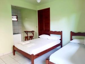 a room with two beds and a table in it at Pousada da Nalva in Rio das Ostras