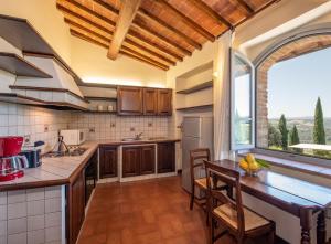 una cucina con tavolo e una grande finestra di Ranuccio Apartment - Dimora di Fulignano a San Gimignano