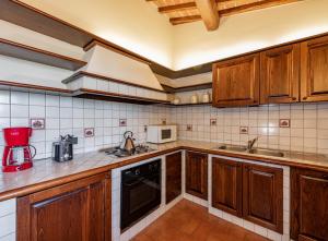 a kitchen with wooden cabinets and a red blender at Ranuccio Apartment - Dimora di Fulignano in San Gimignano
