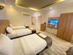 a hotel room with two beds and a flat screen tv at فندق زهرة الياسر مكة in Makkah