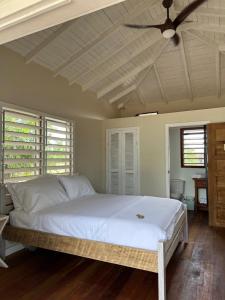 a bedroom with a white bed with a ceiling fan at Belizima Eco Resort in Sarteneja
