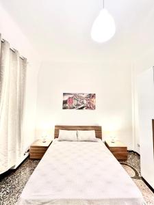 a white bedroom with a large bed and two tables at A due passi da Brignole in Genoa