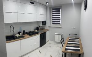 uma cozinha com armários brancos e uma mesa de madeira em Apartament ,,Eden” em Zator