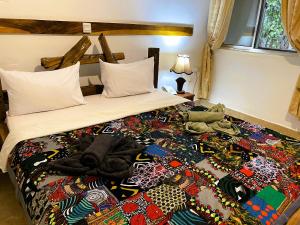 a bed with a colorful blanket on top of it at Home Feeling Neneu Lodge in Moshi