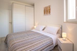 a bedroom with a bed with white sheets and two lamps at Apartment with a private pool, enchanting view, beach - by Traveler tourist agency ID 2122 in Vrbnik